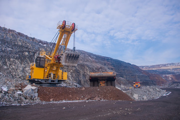 Excavator in the quarry loads the dumper with iron ore. Loading in winter