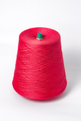 Red bobbin of yarn on a white background.Textile reel on isolated white background.