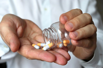 Doctor with pills, man in white lab coat giving medication in capsules. Concept of medical exam, hospital, dose of drugs, vitamins, pharmacy, flu treatment