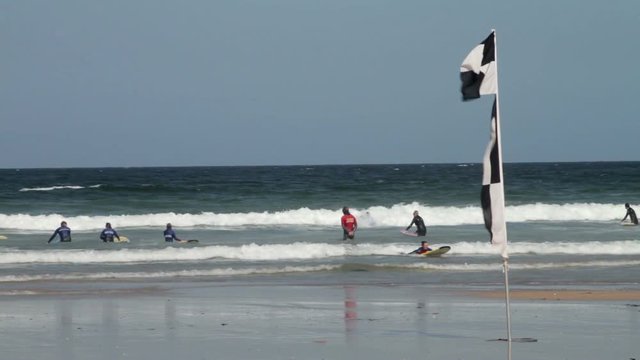 Surfing instructor and school practising in safe area near chequered flag, Great Western Beach, Newquay, Cornwall