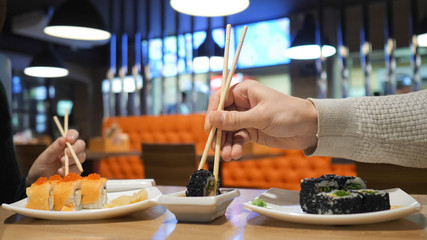 Happy couple eating sushi rolls in japan restaurant, sushi bar. Japanese food, diet, dieting.