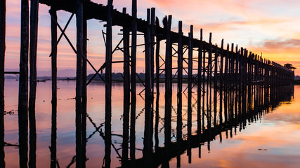 before sunrise iconic U-Bein Bridge, the longest teak foot bridge crosses the shallow Lake Taungthamanin,it's piers  reflecting on the lake, Amarapura, Mandalay, Myanmar