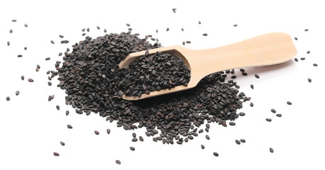 Black organic sesame seeds in wooden spoon isolated on white background