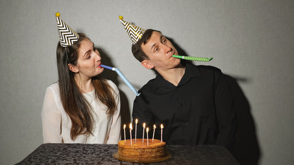 Smiling couple celebrates a holiday playing with party blowers.