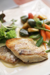 Sea bass fillet with grilled vegetables and salad on wooden table