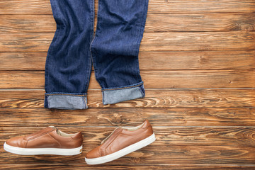 Top view of denim pants and brown shoes on wooden background