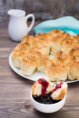 Appetizing slice of monkey bread in black currant jam in a bowl on a wooden table