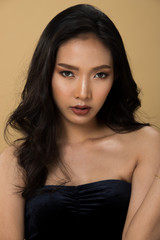 Naklejka premium Fashion Asian Woman Tan skin black curl hair eyes beautiful make up wear black dress strong fest. Studio Lighting gradient shade yellow beige Background