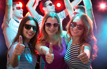 Happy girlfriends showing OK sign in the night club