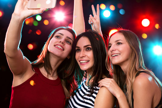 Smiling girls taking selfie in a night club