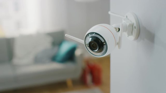 Close Up Object Shot of a Modern Wi-Fi Surveillance Camera with Two Antennas on a White Wall in a Cozy Apartment.
