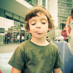 Child with green sweater in the center of Milan in the autumn