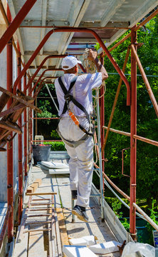 Construction worker mounting a scaffolding structure on a building facade