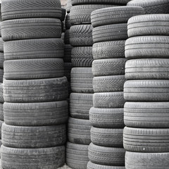 Old used tires stacked with high piles in secondary car parts shop garage