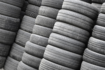 Old used tires stacked with high piles in secondary car parts shop garage