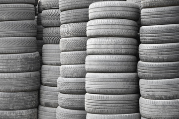 Old used tires stacked with high piles in secondary car parts shop garage
