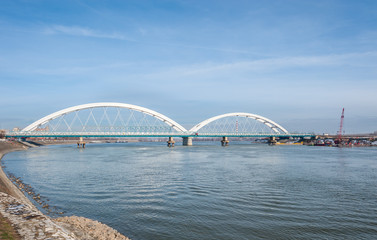 Fototapeta na wymiar New Serbian bridge with arc over the Danube river with architectural lines and blue sky above in city Novi Sad, Serbia