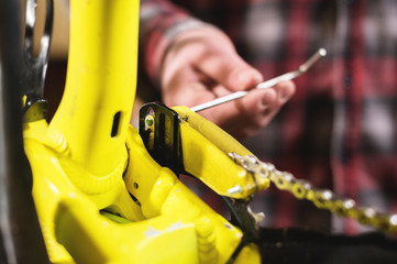 Close-up maintenance of a mountain bike. Male hands adjust the chain tension. Technical condition monitoring in the workshop