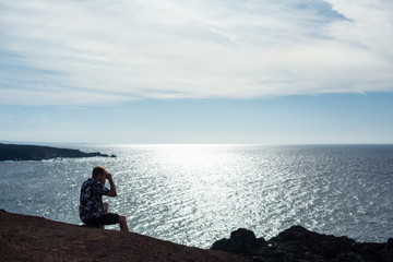 Fototapeta na wymiar A man looks at the sea, sitting on a stone.