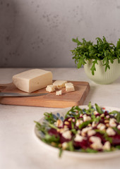 cheese on wooden table and salad with arugula, beetroot, goat cheese