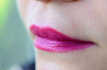Close up shot of woman lips with glossy fuchsia lipstick