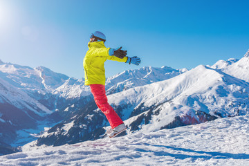 Girl snowboarder jumping and having fun in the winter ski resort.