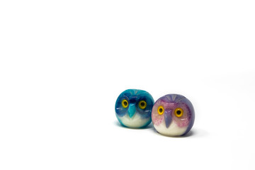 Lucky owl ornament. Small glass lucky object, charm. Blu, azzurro, lilla, viola, giallo. Isolated on white background. Tradition has it that a pair (couple) of owls bring luck.