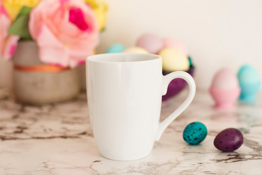 White Mug Mockup - Easter theme. Easter eggs. Colorful eggs in matte colors. Light marble background