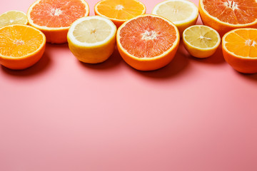 Beautifully sliced oranges, lemons, tangerines and other citruses on a pleasant pink background with copy space. Citrus frame for text