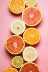 Beautifully sliced oranges, lemons, tangerines and other citruses on a pleasant pink background with copy space. Citrus frame for text