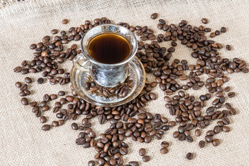 A cup of coffee and coffee beans scattered around.