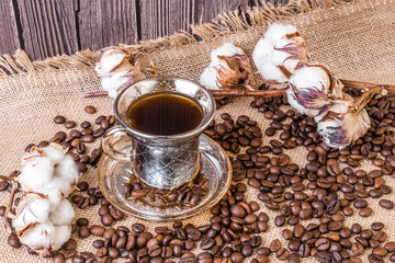 A cup of coffee and coffee beans scattered around.