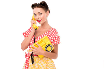 Obraz premium Beautiful pin up girl talking on vintage yellow phone and looking at camera