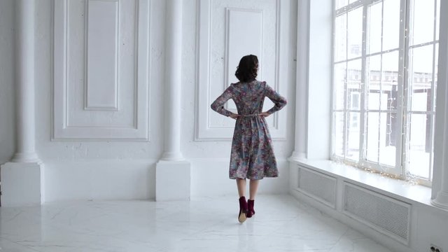 elegant girl in dress smiling and posing in white room with big Windows, slow motion