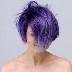 A beautiful, sexy girl with purple hair and a short haircut sits in the middle of the photo with a...