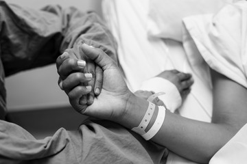 A black and white image of a doctor holding a patients hand