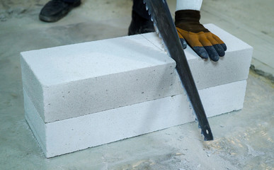 closeup builder sawing aerated concrete block with hand saw