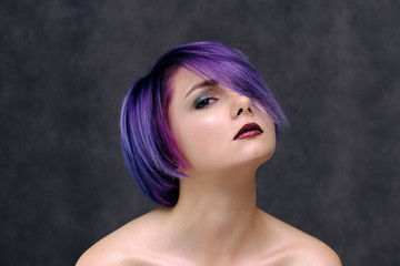 A beautiful, sexy girl with purple hair and a short haircut sits in the middle of the photo with a...