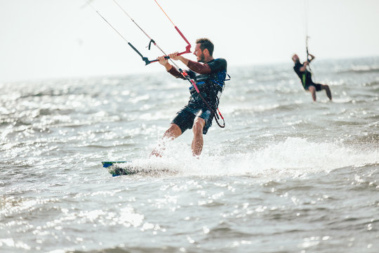 Professional kiter makes the difficult trick on a beautiful background. Kitesurfing Kiteboarding action photos man among waves quickly goes