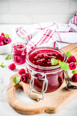 Homemade raspberry jam in two jars with raspberries and mint