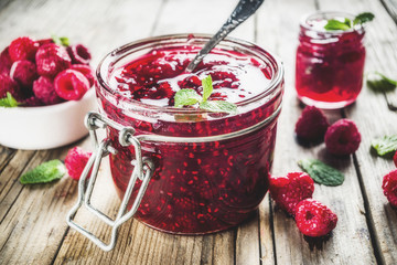 Homemade raspberry jam in two jars with raspberries and mint