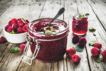 Homemade raspberry jam in two jars with raspberries and mint