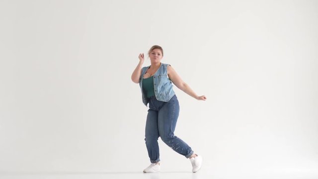 Overweight young woman dancing and having fun on studio background