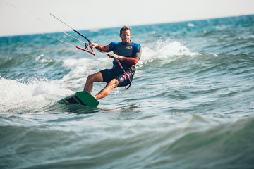 Professional kiter makes the difficult trick on a beautiful background. Kitesurfing Kiteboarding action photos man among waves quickly goes - obrazy, fototapety, plakaty