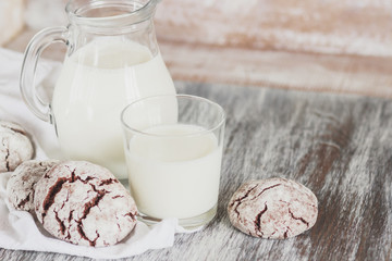 Handmade chocolate cookies, glass and jug with milk, blurred background