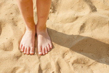 Children's feet on the yellow sea sand