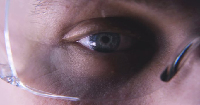 Very close through the glasses you can see the blue eye and its blinking action. Concept of: Sky blue, Working eye, Concentration.