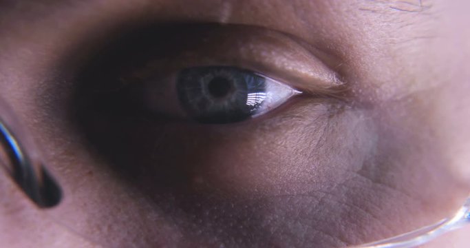 Very close through the glasses you can see the blue eye and its blinking action. Concept of: Sky blue, Working eye, Concentration.