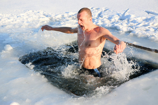 A Young Man Is Preparing To Dive Into The Ice Hole. Winter, Cold, Open Water.