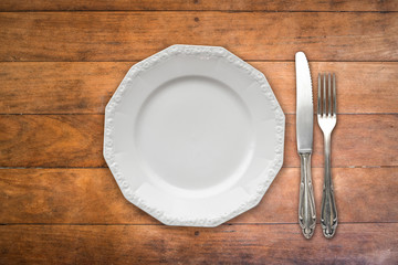 empty plate , fork and knife on wooden table -